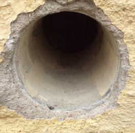 Loch in farbiger Hauswand.